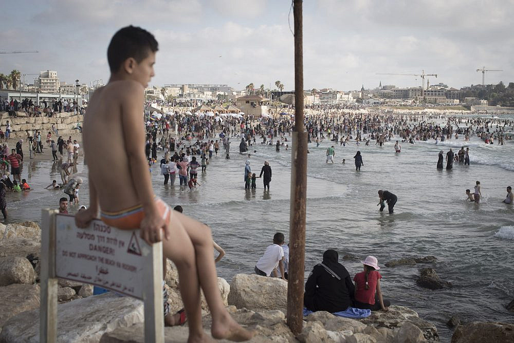 Palestinians bathe in the Mediterranean Sea during the last day of the Eid al-Fitr holiday as the sun sets in Jaffa, July 19, 2015. (Oren Ziv)