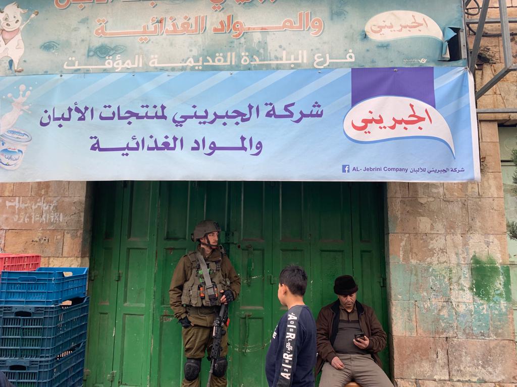 An Israeli soldier stands in front of a Palestinian-owned shop in Hebron's Old City that has been forced to close under orders of the Israeli army, Hebron, occupied West Bank, Jan. 29, 2022. (Basil al-Adraa)