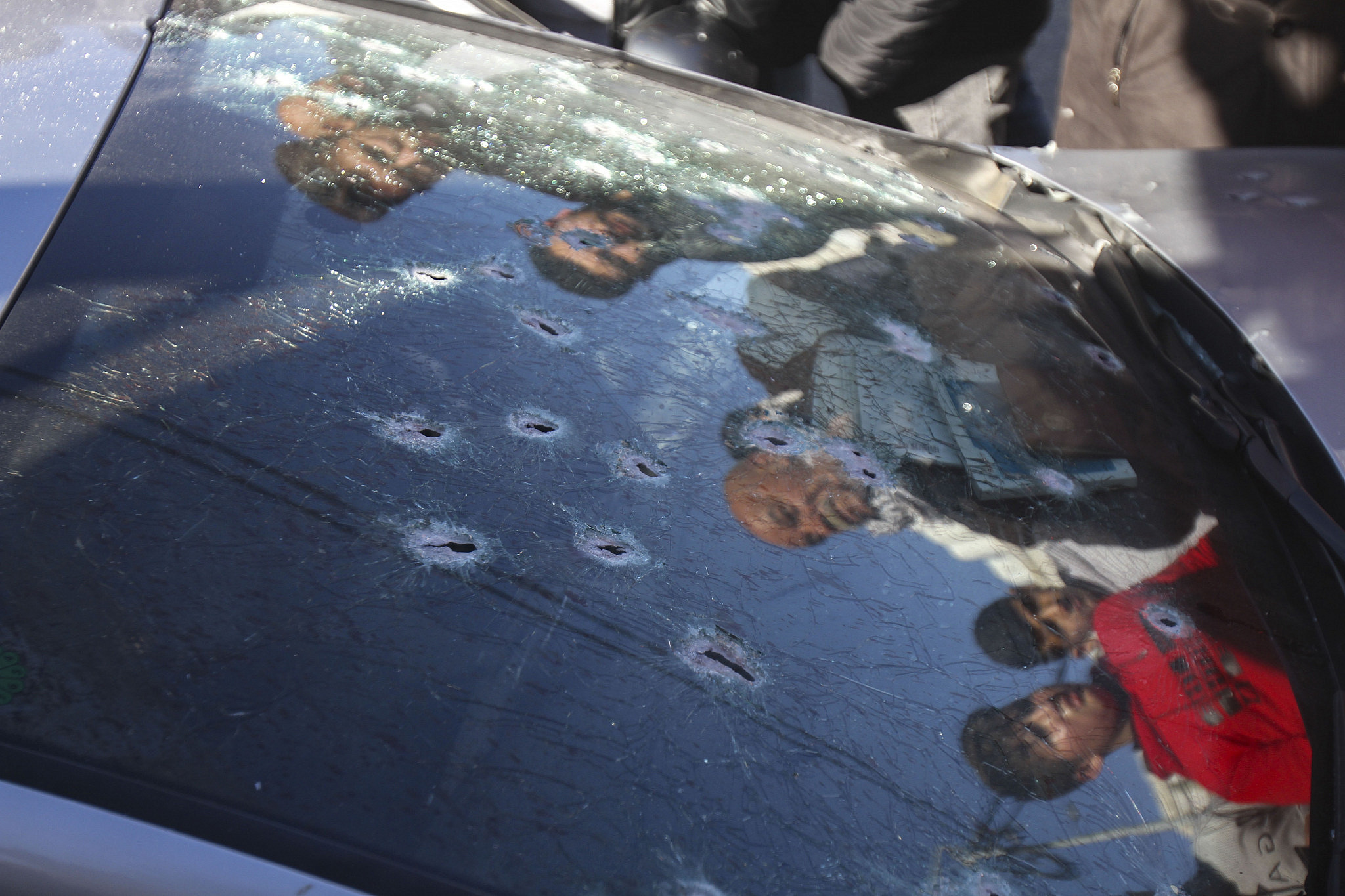 Palestinians look at a car with bullet holes after Israeli security forces killed three Palestinians who were allegedly behind recent shooting attacks against Israeli soldiers and civilians, Nablus, occupied West Bank, February 8, 2022. (Nasser Ishtayeh/Flash90)