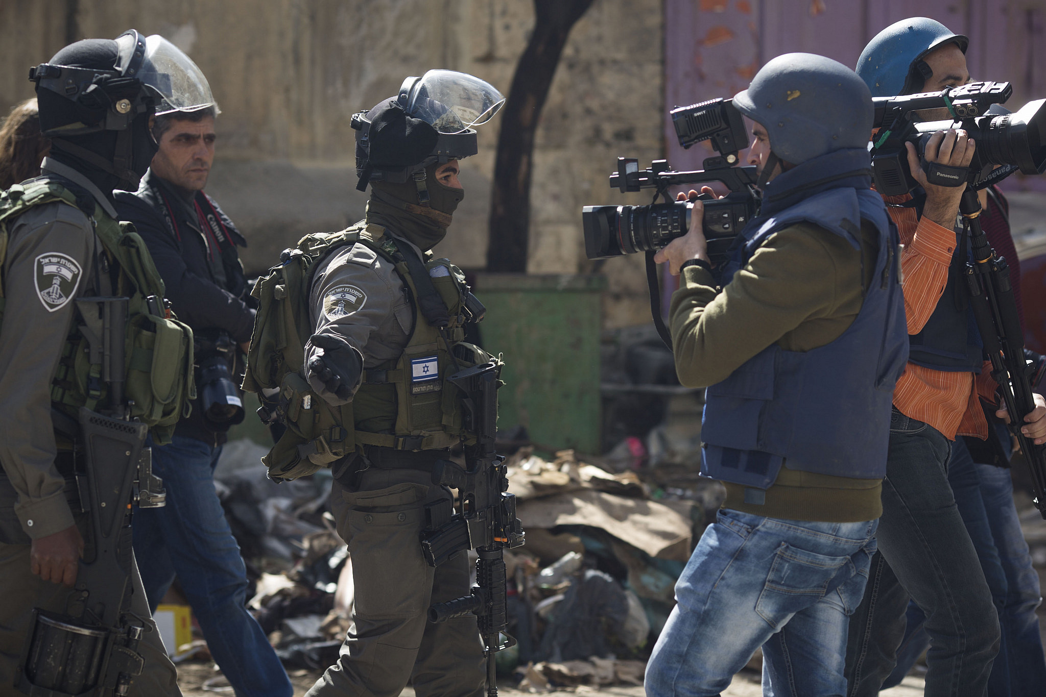 An Israeli border policeman orders a Palestinian journalist to leave the area during a protest against the closure of Shuhada Street to Palestinians, in the West Bank city of Hebron, February 21, 2014. (Oren Ziv/Activestills)