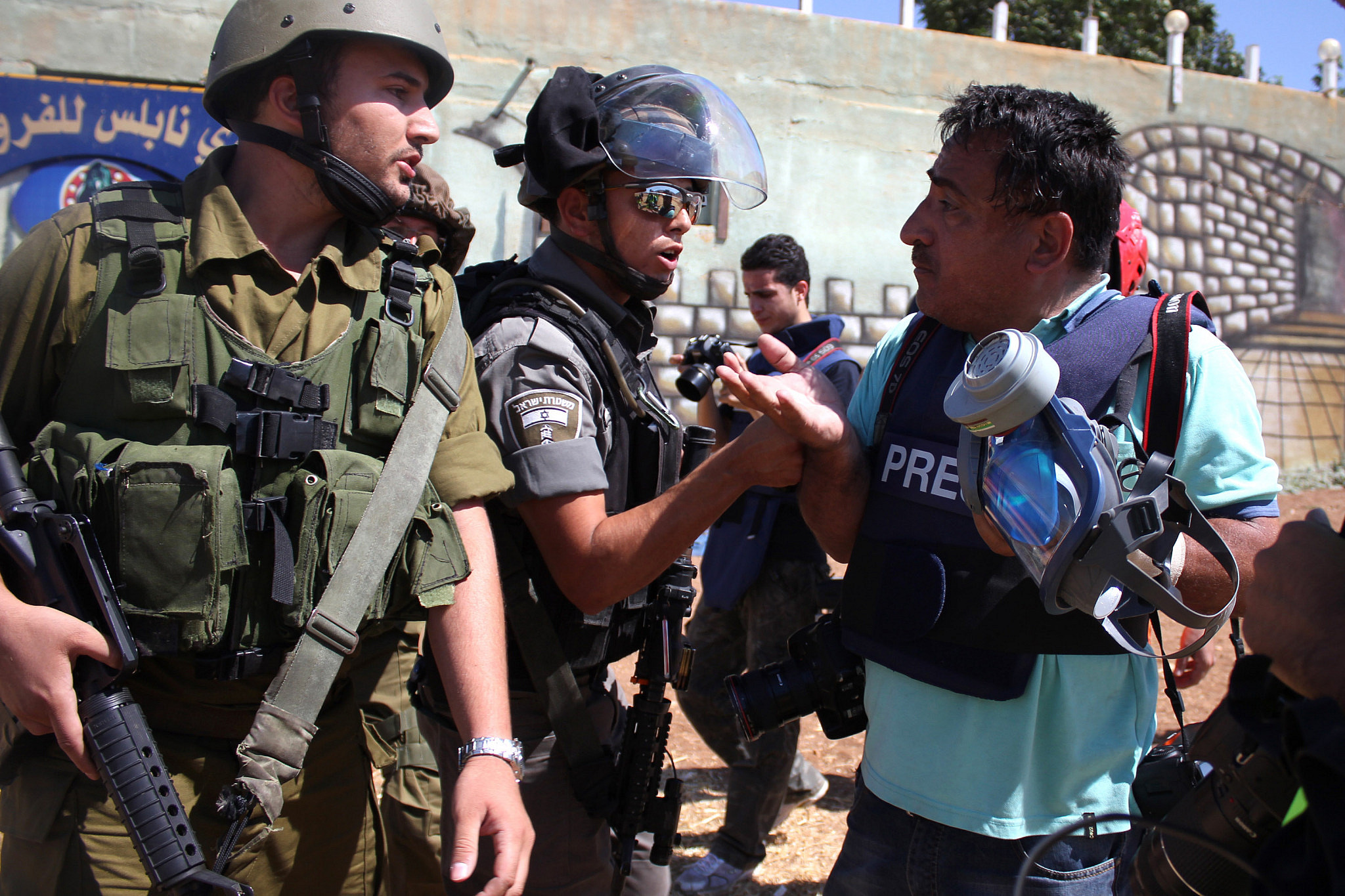 Israeli soldiers try to prevent a Palestinian photojournalist from covering clashes that followed a demonstration in solidarity with the Gaza Strip at Beit Furik military checkpoint, Nablus, West Bank, August 8, 2014. (Ahmad Al-Bazz/Activestills)