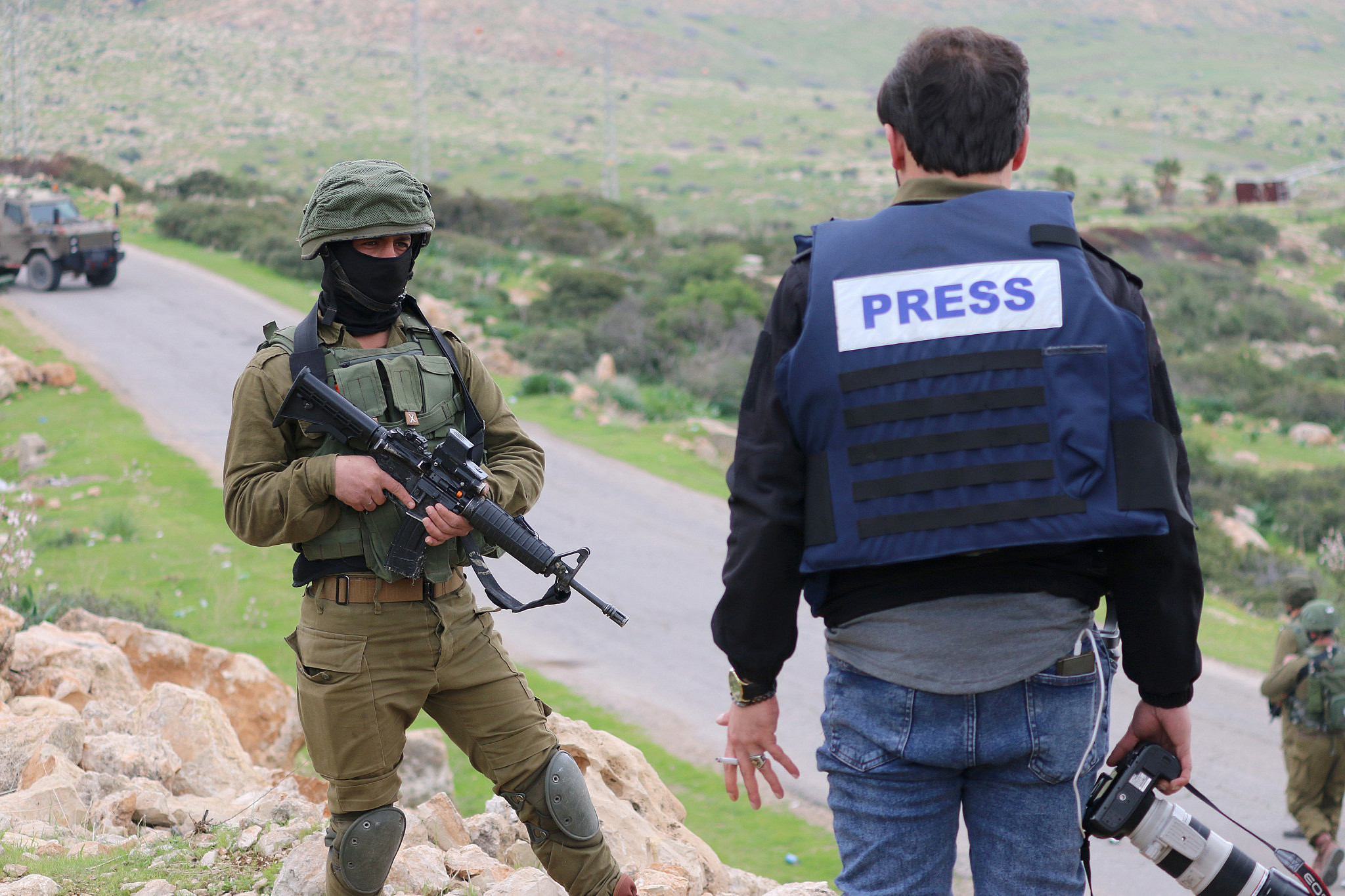 An Israeli soldier watches a Palestinian journalist during a protest against the Trump Plan, in the Jordan Valley, West Bank, February 25, 2020. (Ahmad Al-Bazz/Activestills)