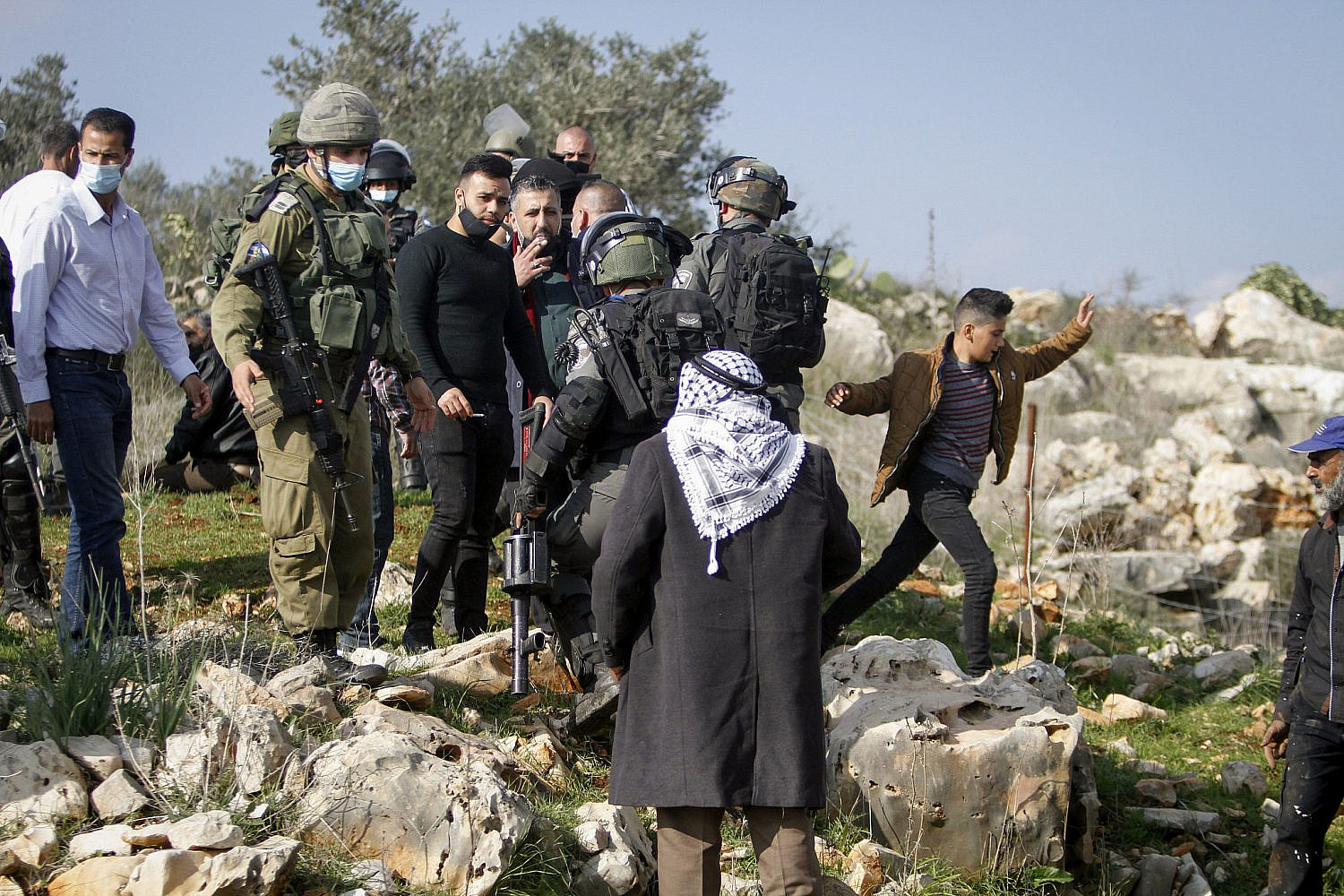 Israeli soldiers surround Palestinians planting olive trees near the settlement of Ariel in the West Bank. December 22, 2020. (Nasser Ishtayeh/Flash90)