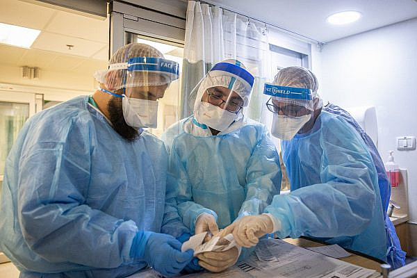 Medical team members wearing safety gear as they work in the coronavirus ward of the Hadassah Ein Kerem Medical Center in Jerusalem, August 25, 2021. (Yonatan Sindel/Flash90)