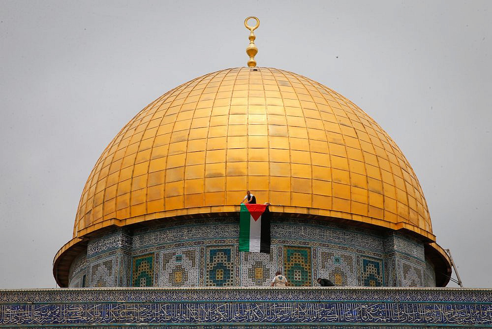 A man place a Palestinian flag on the Dome of the Rock after Friday prayers of the holy month of Ramadan at Al-Aqsa compound in Jerusalem's Old City, Friday, April 22, 2022. (Jamal Awad/Flash90)