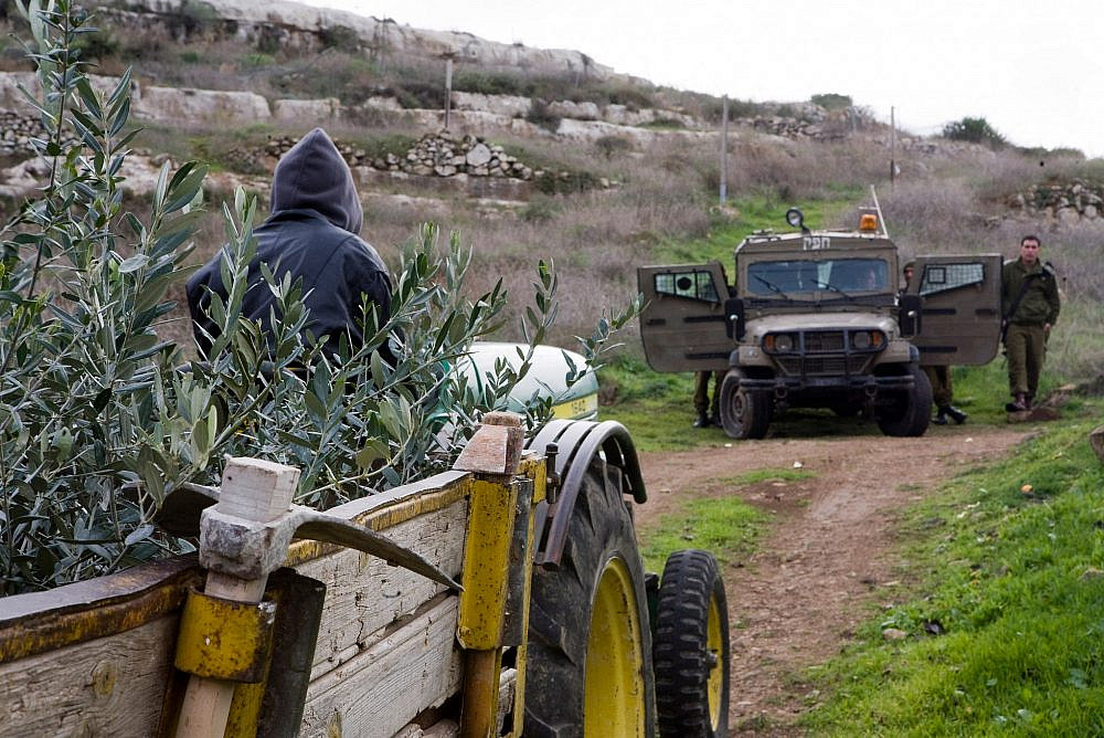 Israeli army blocks the road for a Palestinian driving a tractor, during an olive planting action in the village of Deir Nizzam, Ramallah district, West Bank, December 15, 2009. (Keren Manor/Activestills)