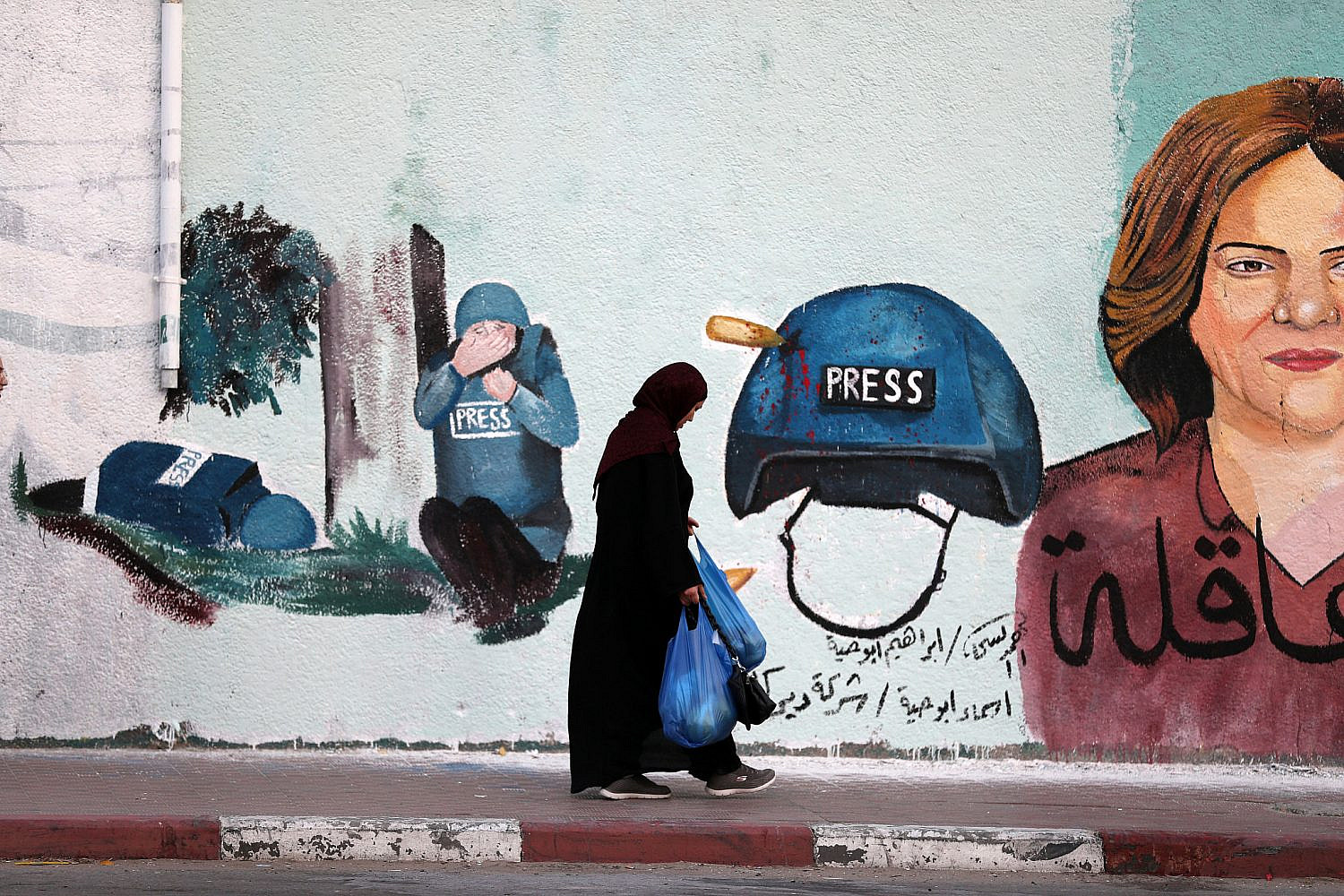 Women passing next to a mural honoring Palestinian journalist Shireen Abu Akleh in Gaza City, May 12, 2022. (Mohammed Zaanoun/Activestills)
