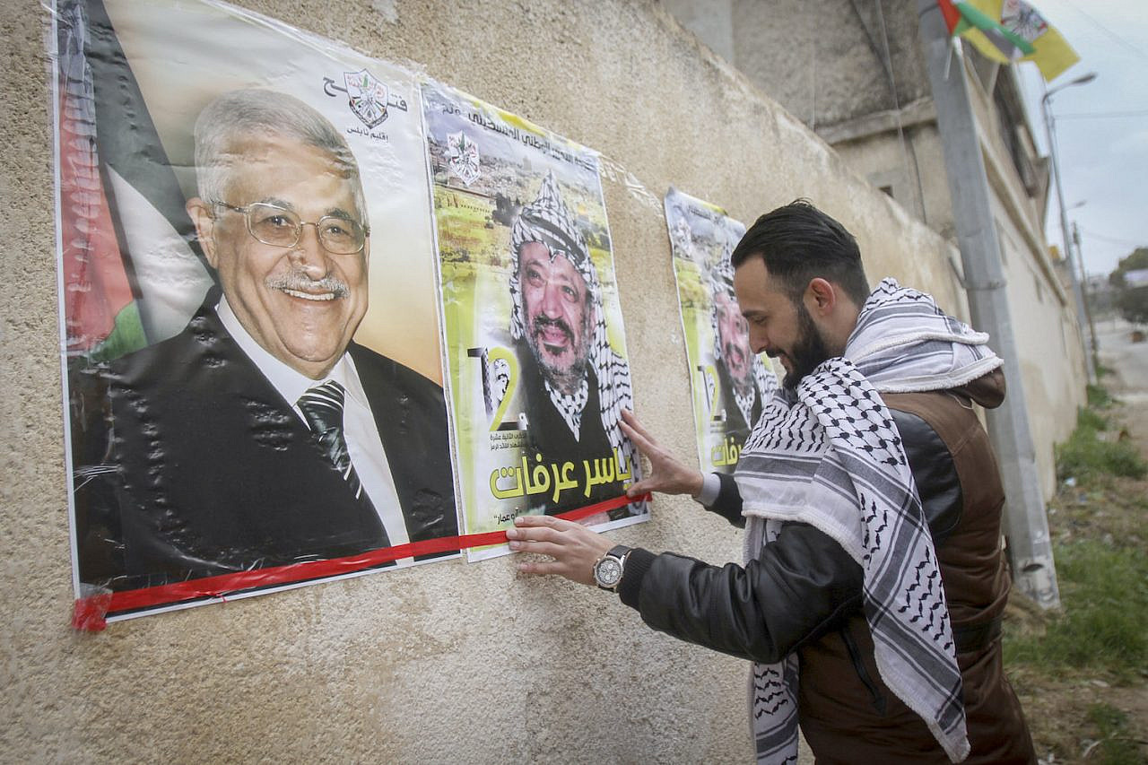 Palestinians hang posters depicting Yasser Arafat and Palestinian President Mahmoud Abbas, Nablus, West Bank, March 14, 2017. (Nasser Ishtayeh/Flash90)
