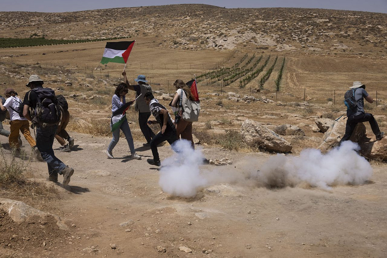 Palestinian, Israeli, and international Jewish activists flee from tear gas fired by Israeli soldiers to disperse a protest against the expulsion of the Palestinian communities that live inside what Israel calls Firing Zone 918, Masafer Yatta, occupied West Bank, June 10, 2022. (Oren Ziv)