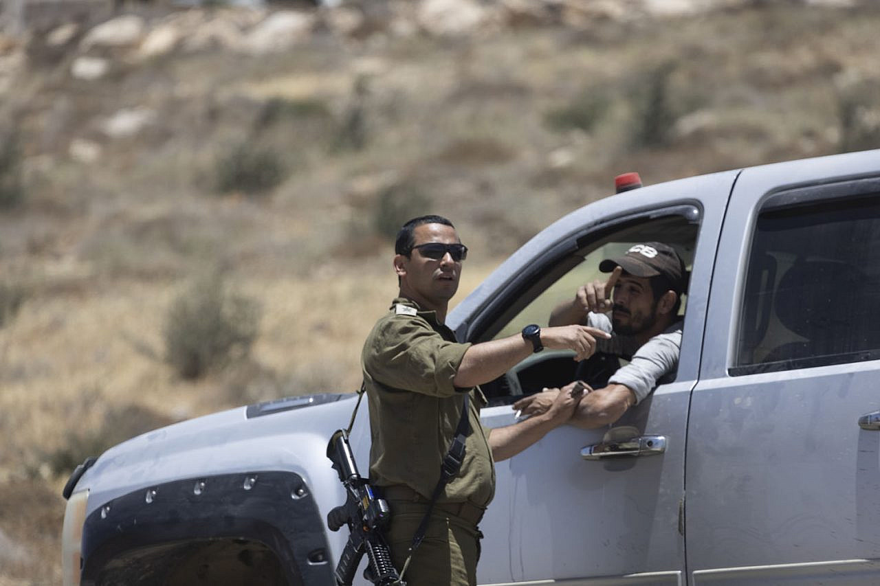 Col. Yehuda Rosilio, incoming brigade commander of the Judea area of the West Bank, speaks to the driver of the vehicle that blocked the exit of the car belonging to left-wing activists while another settler attacked it with stones, Masafer Yatta, occupied West Bank, June 10, 2022. (Oren Ziv)