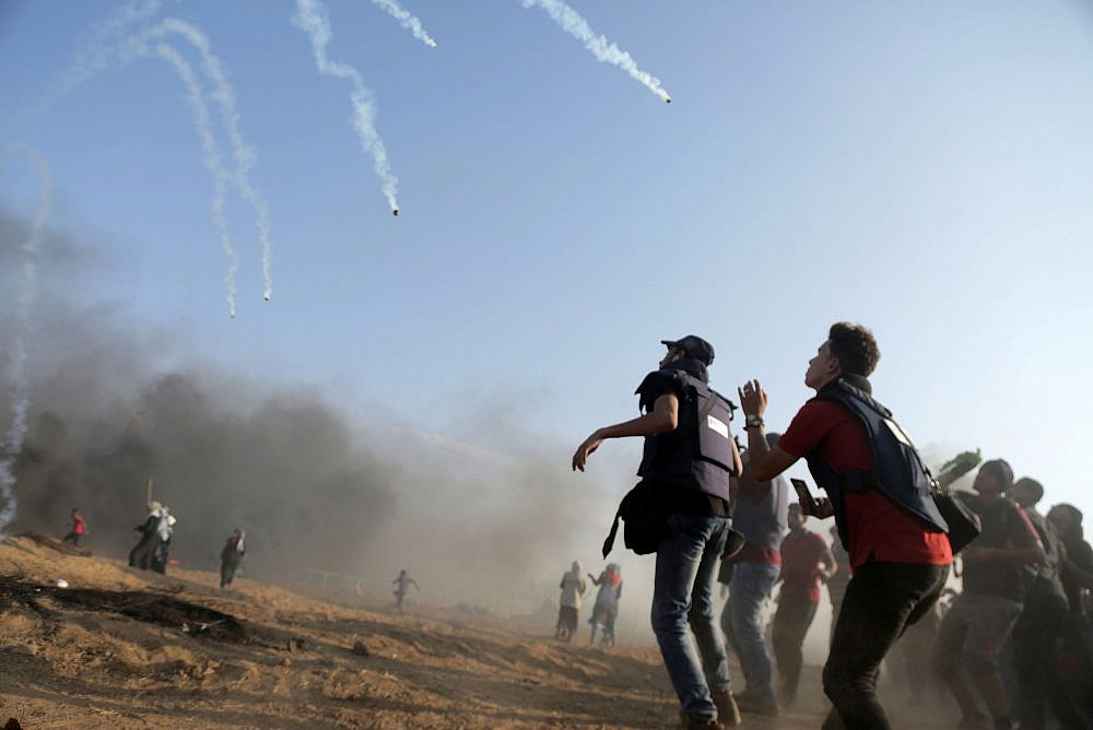 Tear gas fired by the Israeli army lands on Palestinian journalists, during the 27th "Great March of Return" Friday protest near the Gaza-Israel fence, Gaza Strip, September 28, 2018. (Mohammed Zaanoun/Activestills)