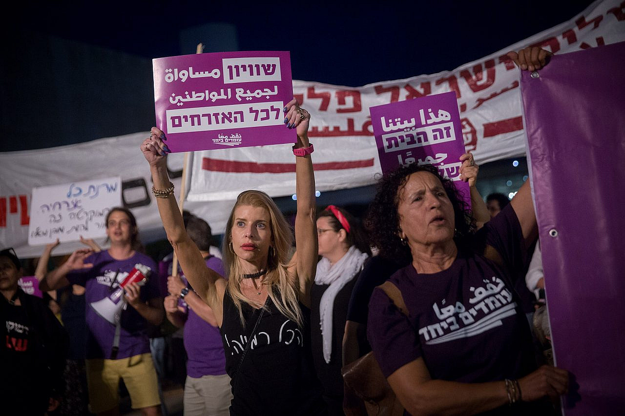 Activists from the Standing Together movement hold up signs in support of peace and equality at a demonstration in HaBima Square, Tel Aviv, May 22, 2021. (Miriam Alster/Flash90)