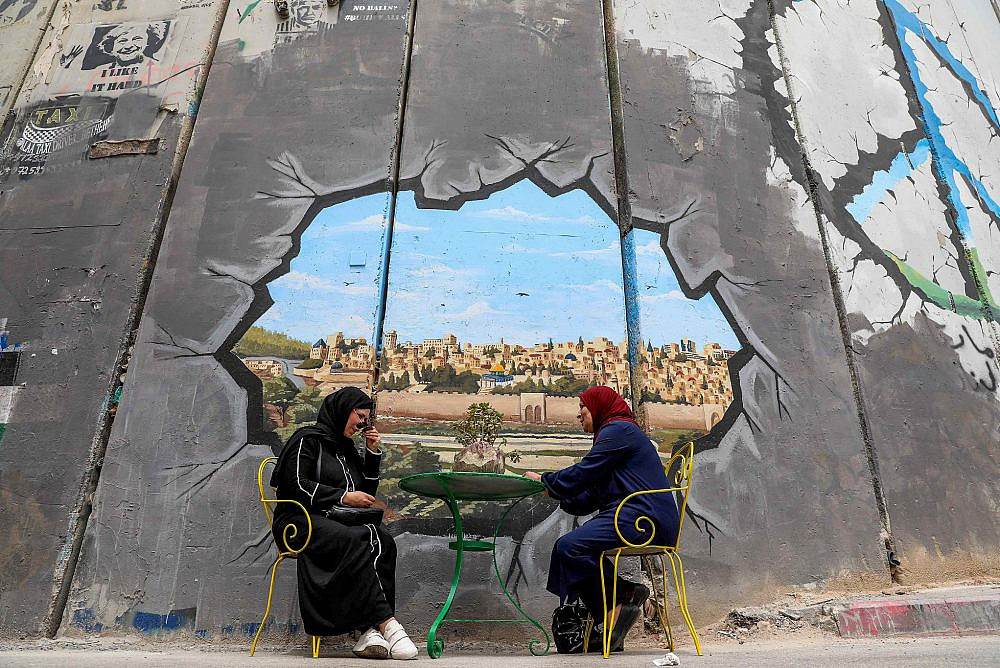People next to a mural showing Al-Aqsa Mosque compound and Jerusalem's Old City, on the separation barrier between Jerusalem and the West Bank city of Bethlehem, April 18, 2022. (Wisam Hashlamoun/Flash90)