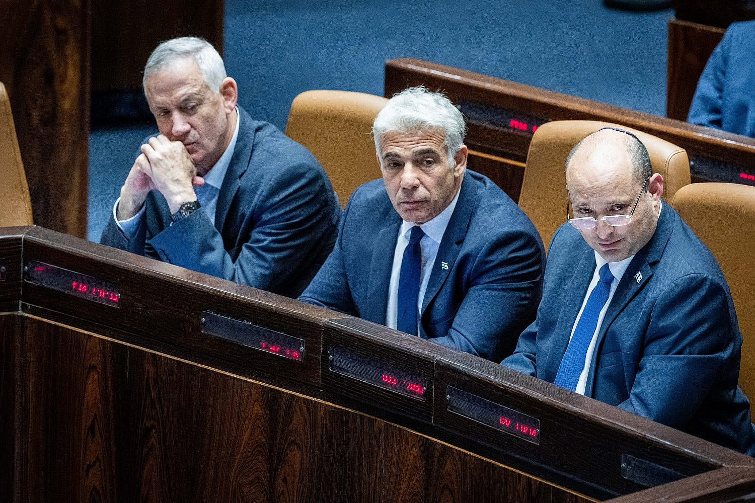 Israeli prime minister Naftali Bennett, Foreign Affairs Minister Yair Lapid, and Defense Minister Benny Gantz seen during a discussion on the vote on the "settler law bill" at the Knesset, Jerusalem, June 6, 2022. (Yonatan Sindel/Flash90)