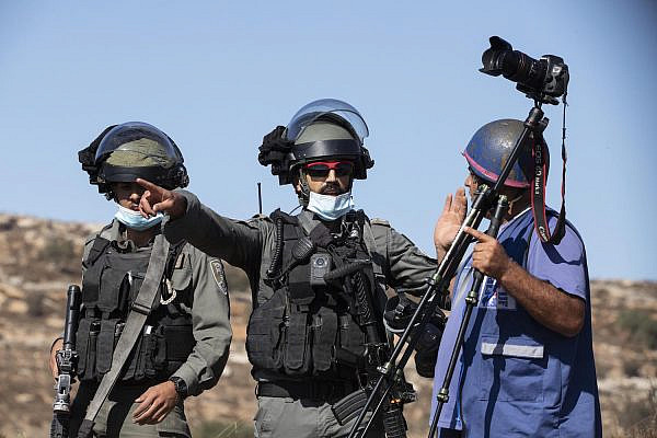 Border Police officers force a Palestinian cameraman to leave the area during the Palestinian olive harvest, near an illegal outpost close to the village of Burka, West Bank, October 16, 2020. (Oren Ziv)