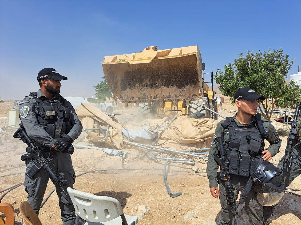 Israeli police stand in front of a bulldozer demolishing homes in Masafer Yatta in front of the occupied West Bank, June 1, 2022. (B'Tselem)