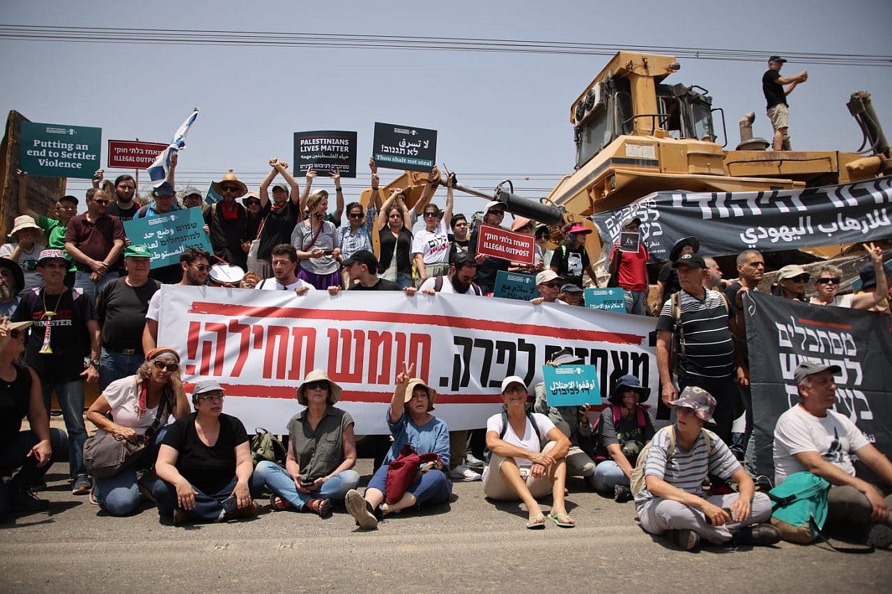 Left-wing Israeli activists gather for a photo in front of a bulldozer ahead of a protest organized by Peace Now against the Homesh outpost, May 28, 2022. (Oren Ziv)