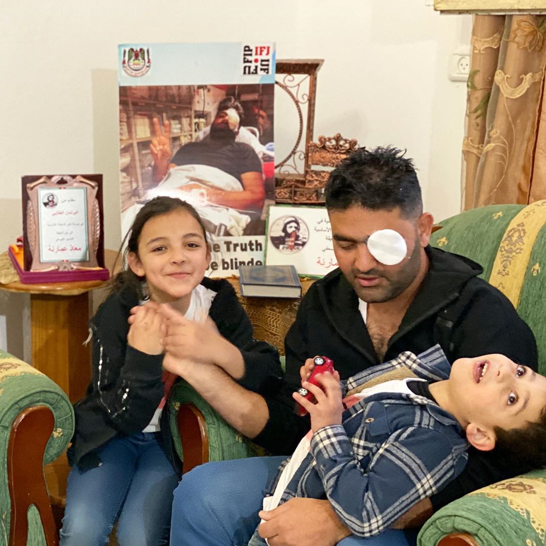 Moath Amarnih, a Palestinian photojournalist who was shot in the eye by Israeli soldiers in 2019, at his home with his children. (Courtesy of Amarnih)
