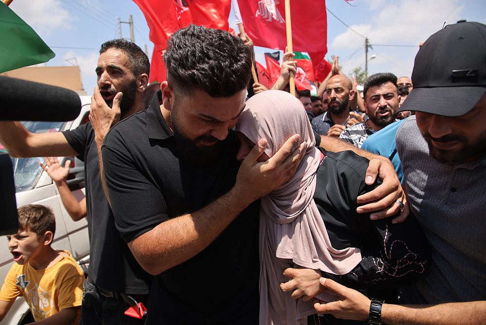 Palestinians comfort the mother of Ali Hasan Harb, whose son was stabbed and killed by an Israeli settler in the West Bank, during his funeral, Iskaka, June 22, 2022. (Oren Ziv)
