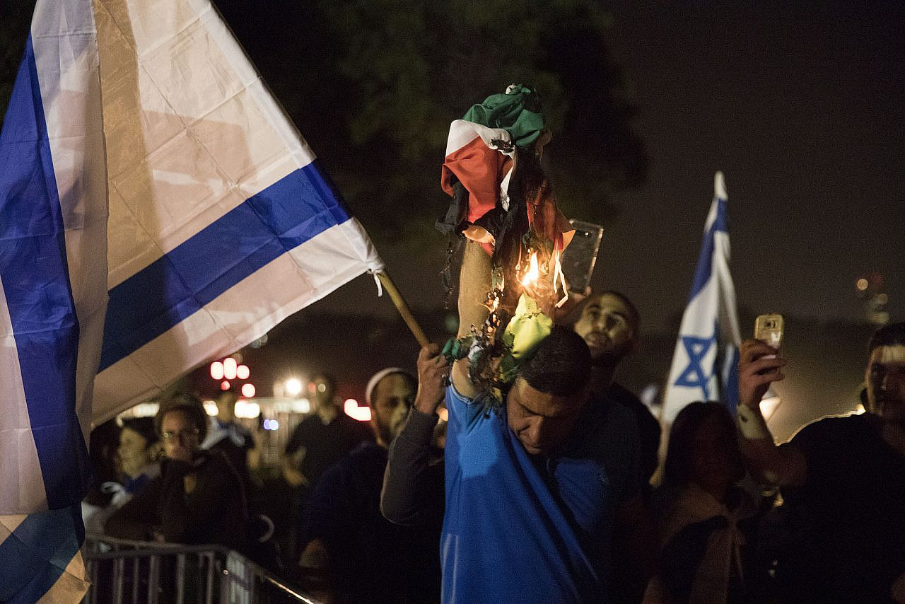 Right-wing Israelis hold Israeli flags and burn Palestinian flags outside the 13th Joint Israeli-Palestinian Memorial Day ceremony, Tel Aviv, April 17, 2018. (Oren Ziv/Activestills)