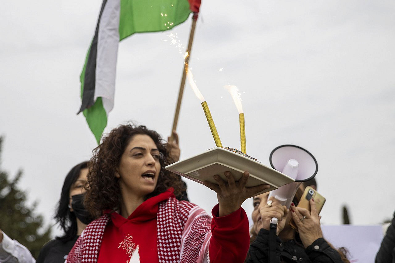 A protester holds a cake to mark the birthdays of political prisoners in detention in Damoun Prison, where dozens of Palestinian minors are held, Haifa, December 4, 2021. (Heather Sharona Weiss/Activestills)