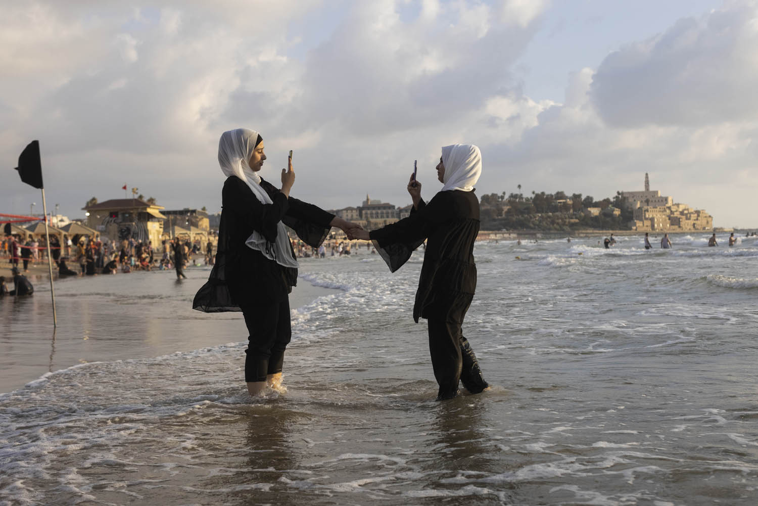 Palestinian women take photos of each other at the beach in Jaffa during the Eid al-Adha holiday, July 11, 2022. (Oren Ziv)