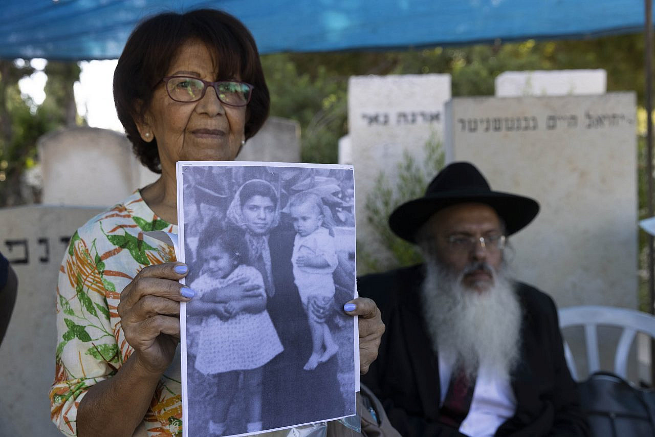 A family member of Yosef Melamed shows a photo of him as a child on the day that an Israeli forensic team from the Health Ministry opened Melamed's grave for a DNA sample, Nahalat Yitzhak Cemetery, Tel Aviv, July 27, 2022. Melamed's family, who immigrated from Yemen, are sure he was kidnapped as hundreds of children from Middle Eastern and North African countries in the 1940’s and 1950’s. (Oren Ziv)