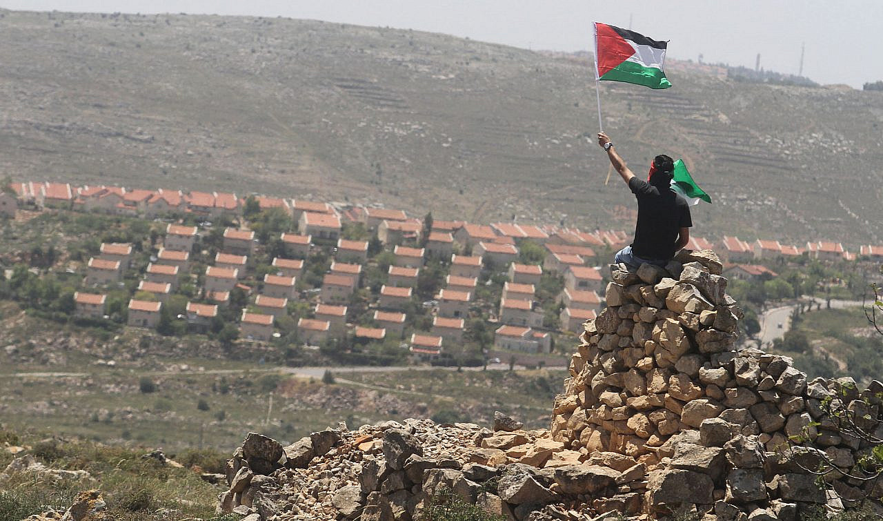 A demonstrator from Deir Jarir waves a Palestinian flag following a march against construction on Palestinian land by residents of the Jewish settlement of Ofra, occupied West Bank, April 26, 2013. (Issam Rimawi/Flash90)