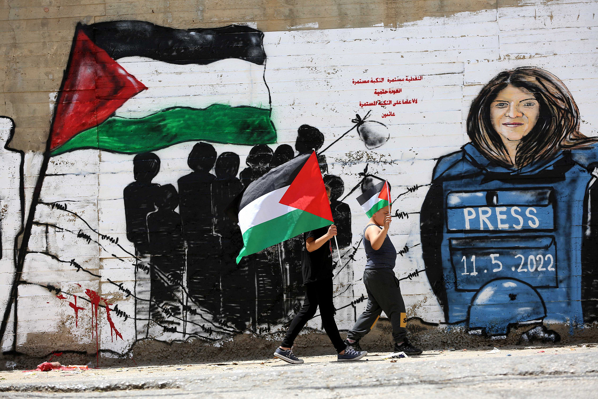 Palestinians walk past a mural for Al Jazeera journalist Shireen Abu Akleh in the West Bank city of Bethlehem, May 16, 2022. (Wisam Hashlamoun/Flash90)