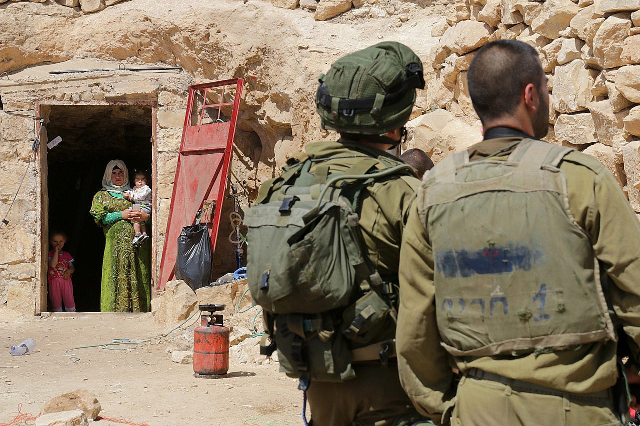 Israeli soldiers stand in front a cave in which a Palestinian family lives in Sarura, South Hebron Hills, during the second military raid on the Sumud Freedom Camp, May 25, 2017. (Activestills/Ahmad Al-Bazz)