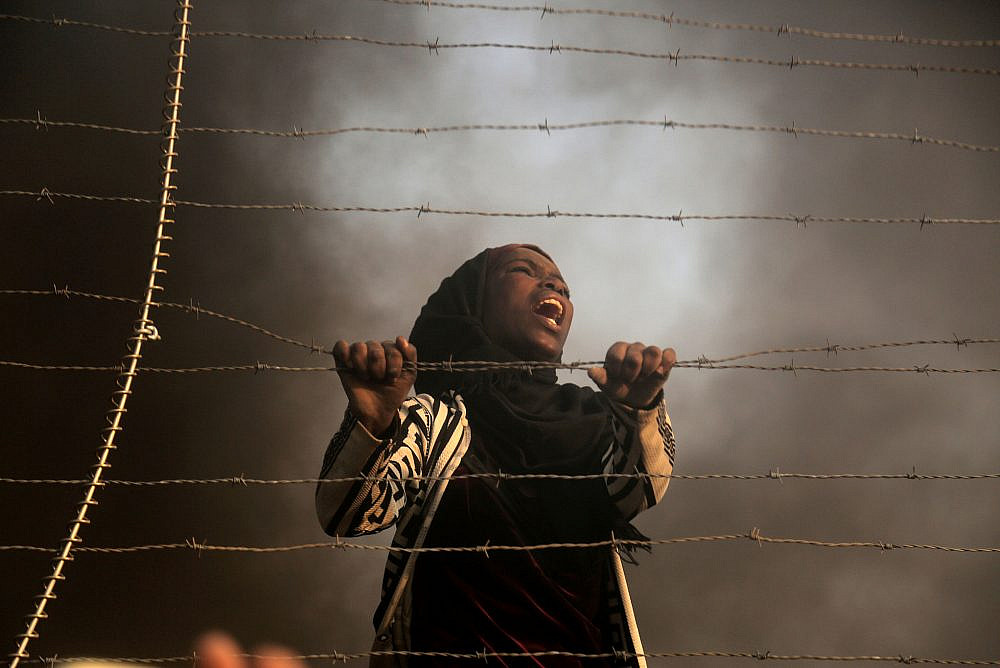 A Palestinian woman climbs the fence separating Israel from Gaza, during the 27th "Great March of Return" Friday protest, Gaza Strip, September 28, 2018. (Mohammed Zaanoun/Activestills)