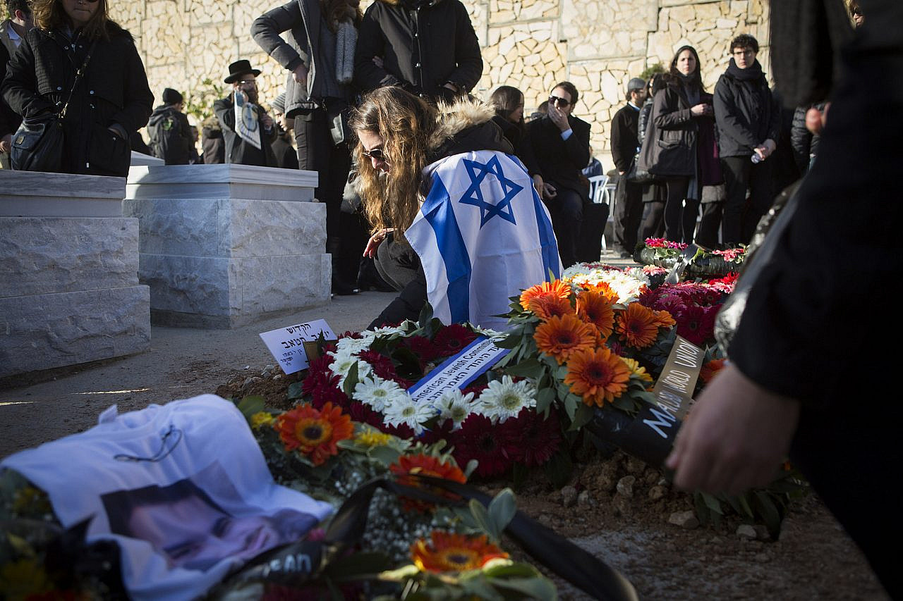 Mourners stand near the graves of four Jews killed in an Islamist attack on a kosher supermarket in Paris, during their funeral in cemetery in Jerusalem, January 13, 2015. (Oren Ziv/Activestills)