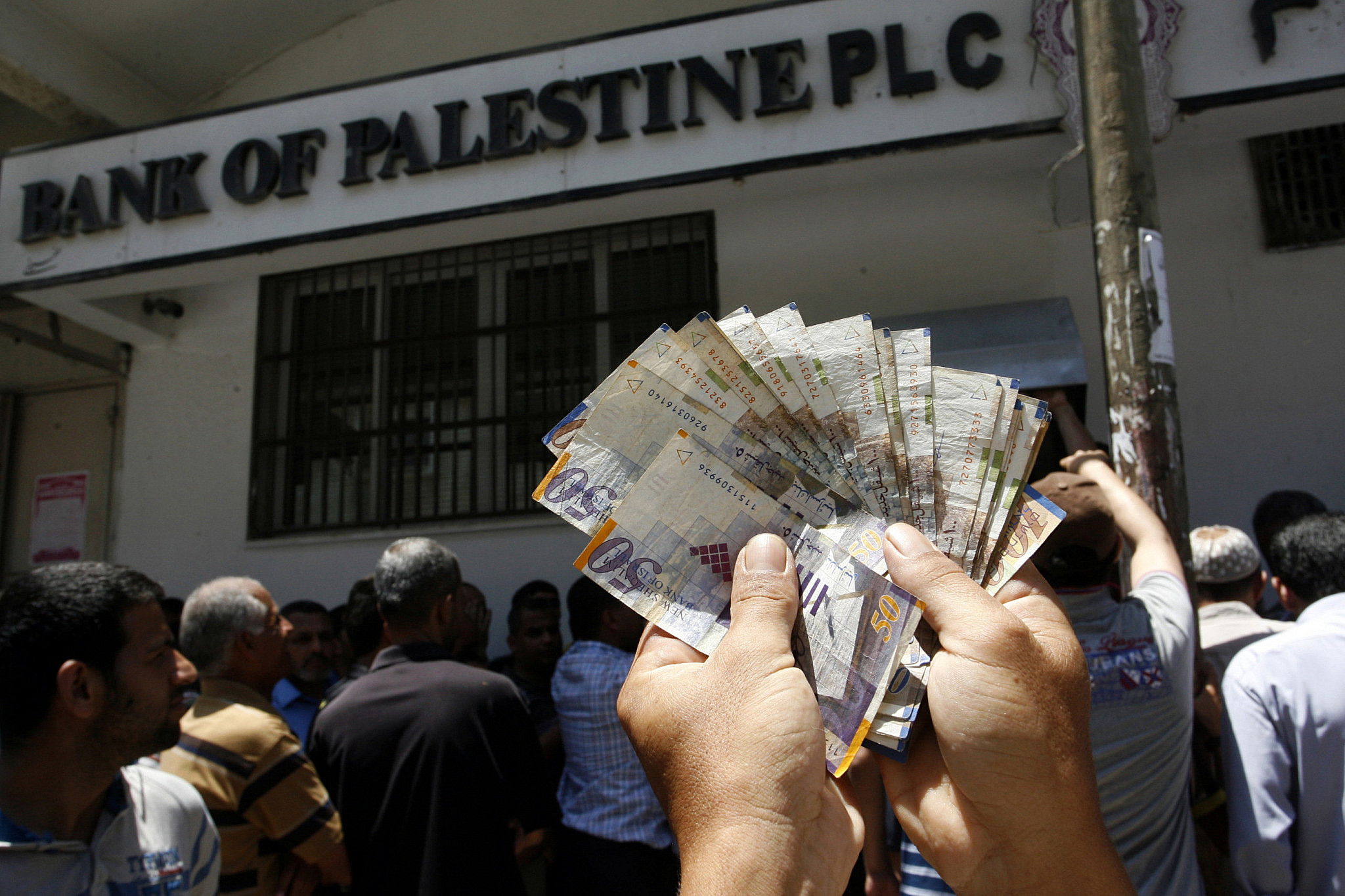 An employee of the Palestinian Authority shows the money he withdrew from a bank in Gaza City, June 11, 2014. (Abed Rahim Khatib/Flash90)