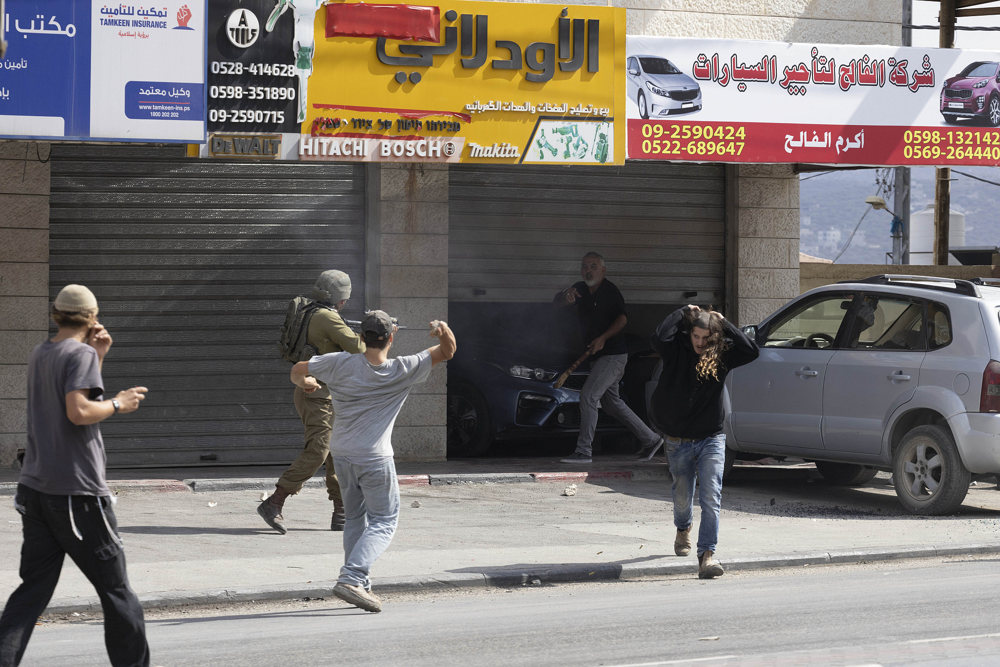 Israeli settlers, backed by Israeli army forces, attack Palestinian residents, cars and shops in the West Bank town of Huwara, near Nablus, October 13, 2022. (Oren Ziv/Activestills)