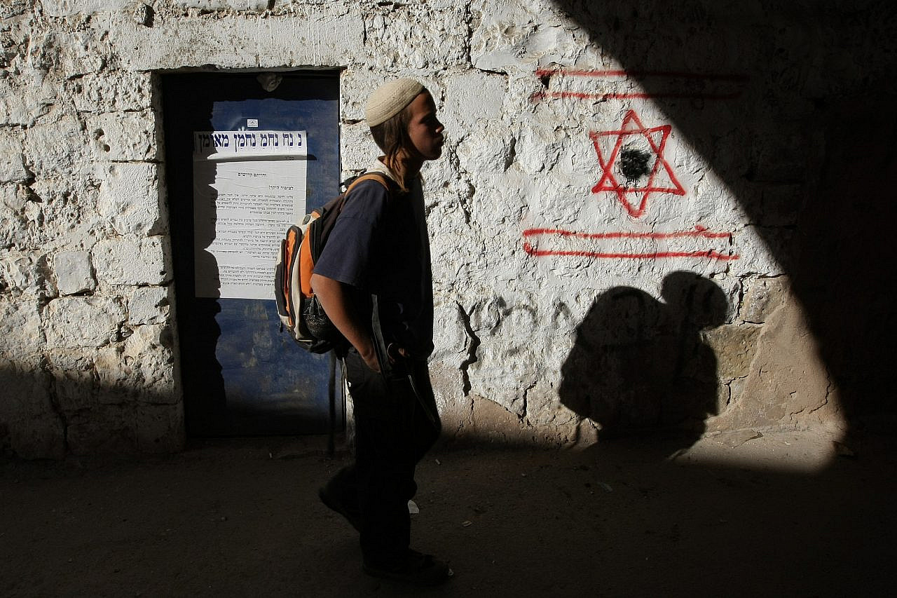 A young settler walks past a star of David painted onto a wall in Hebron, occupied West Bank, December 3, 2008. (Kobi Gideon/FLASH90)