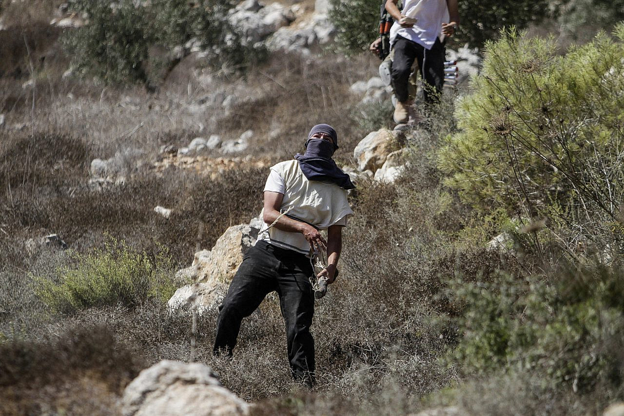 Israeli settlers hurl stones at Palestinians during the annual olive harvest near the Israeli settlement of Yitzhar, occupied West Bank on October 7, 2020. (Nasser Ishtayeh/Flash90)