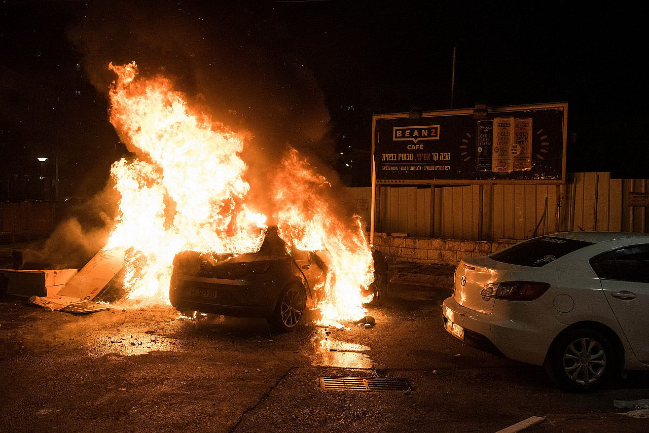 A car is set on fire during clashes between Arabs and Jews in Acre/Akka, northern Israel, May 12, 2021. (Roni Ofer/Flash90)