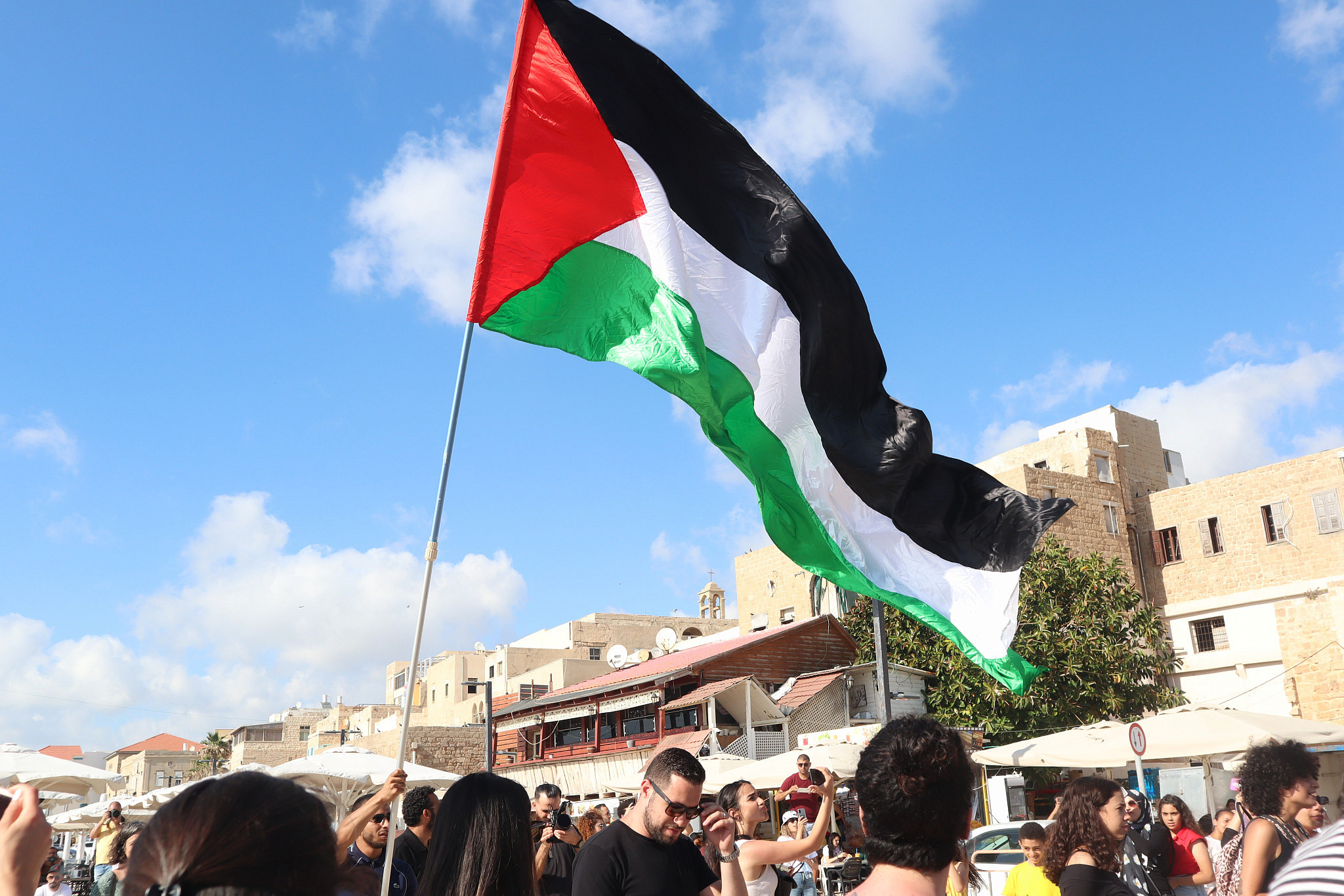 A Palestinian flag waving during 'Palestine Economy Week,' a few weeks after the Unity Intifada, in Akka, June 5, 2021. (Amjad Iraqi)