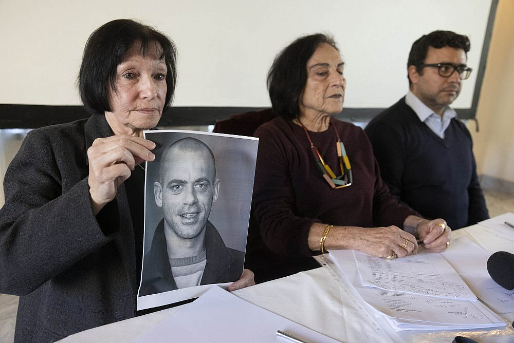 Salah Hammouri's mother (left), alongside Attorney Leah Tsemel (center) and Munir Nuseibeh (right), holds up a photo of him at an emergency press conference in Jerusalem, December 2, 2022. (Oren Ziv)