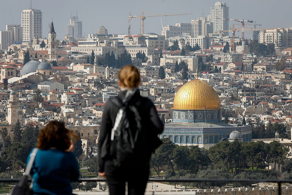Tourists look at a view of the Dome of the Rock and the Temple Mount in Jerusalem's Old City, from the Mount of Olives observatory, January 28, 2020. (Olivier Fitoussi/Flash90)