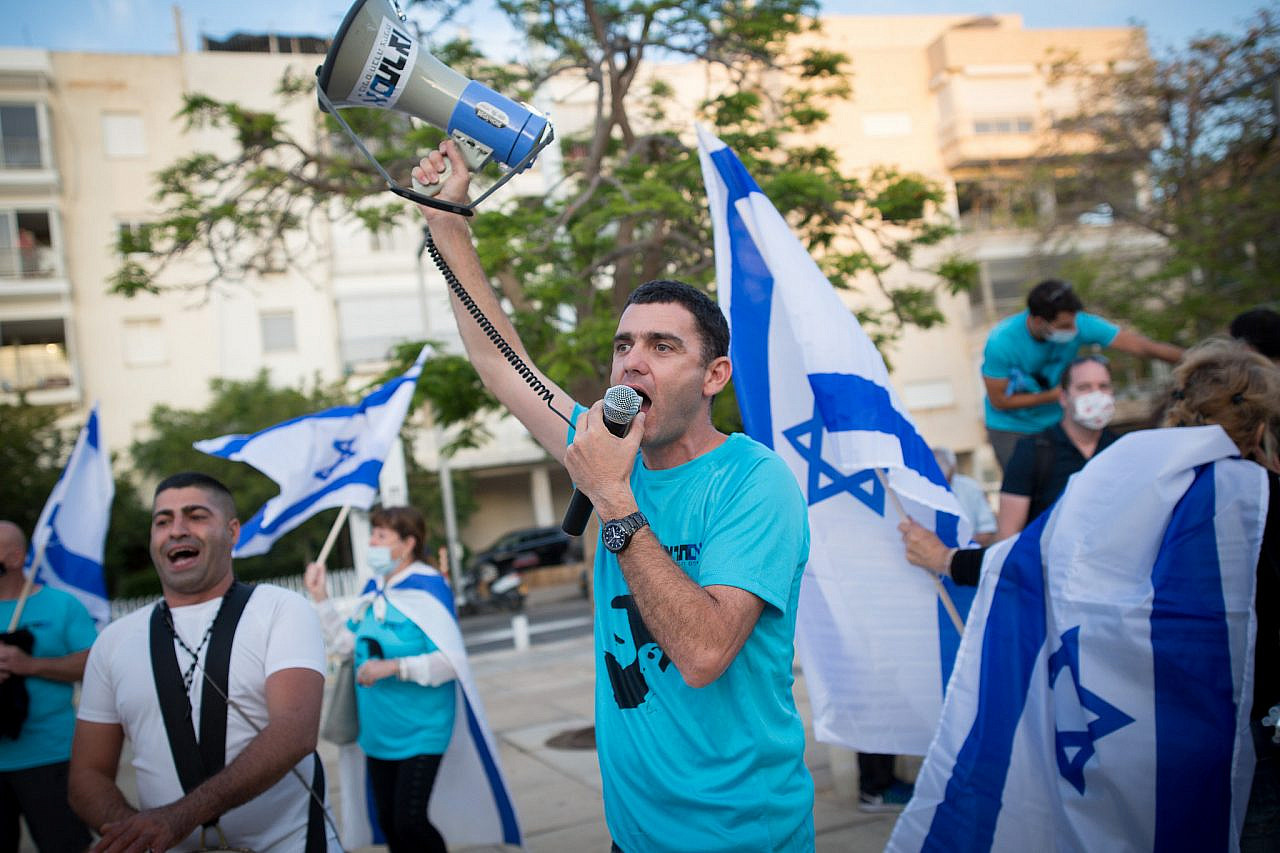 Activists from the right-wing Im Tirtzu movement hold Israeli flags as they protest against Supreme Court President Esther Hayut in HaBima Square, Tel Aviv, May 26, 2020. (Miriam Alster/Flash90)