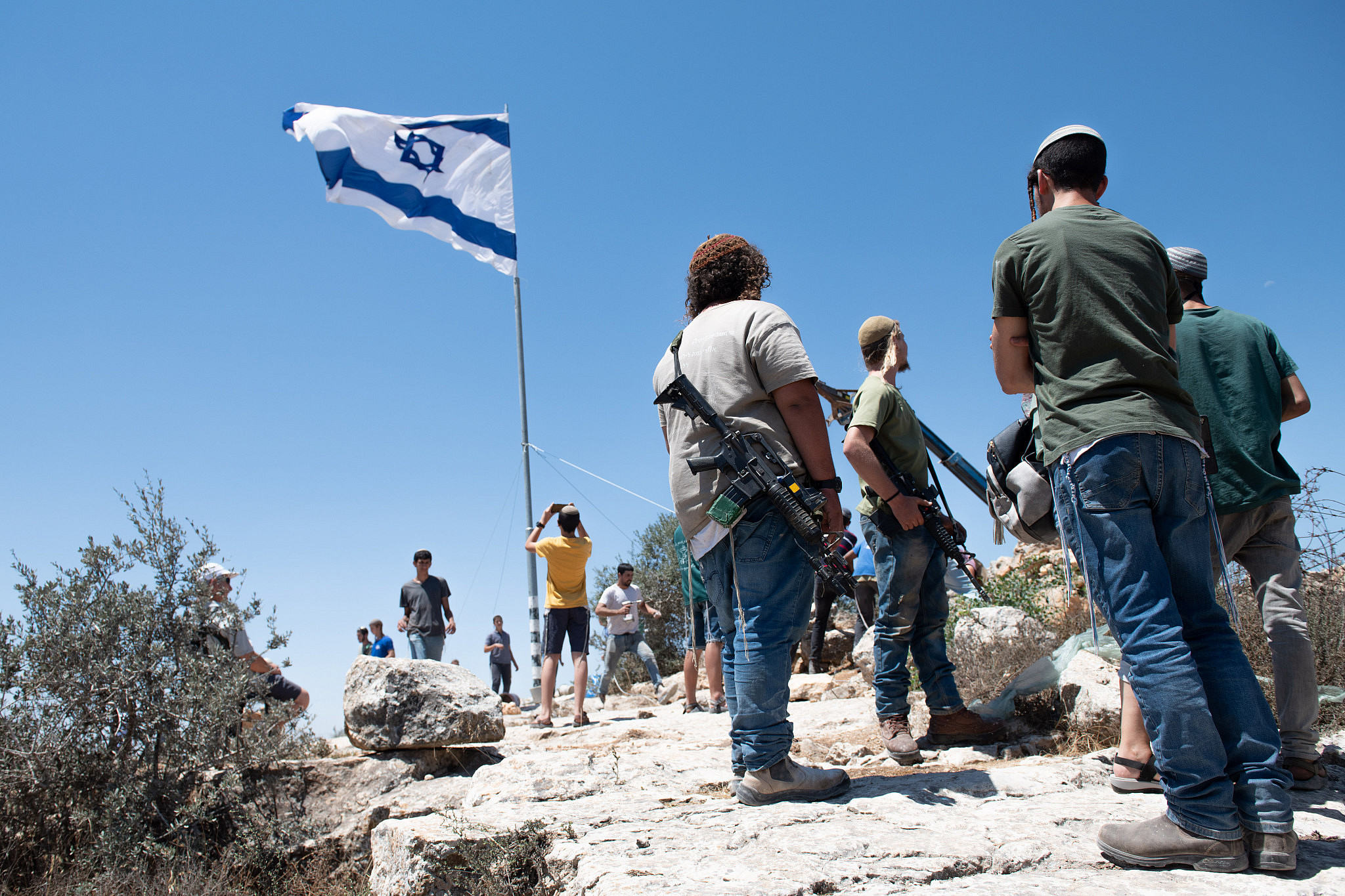 Jewish settlers place up a large Israeli flags at the illegal settlement outpost of Evyatar, before it evacuation as part of a deal with the government, July 2, 2021. (Sraya Diamant/Flash90)
