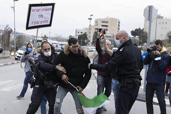 Israeli police confiscate a Palestinian flag from a demonstrator in Sheikh Jarrah, occupied East Jerusalem, December 31, 2021. (Oren Ziv)
