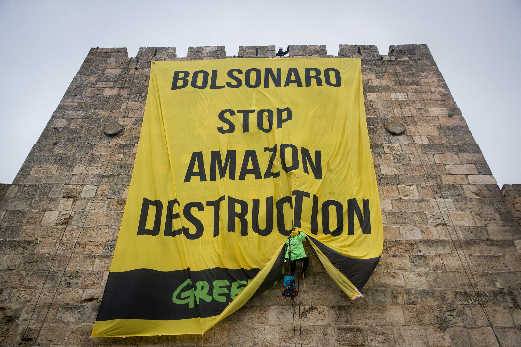 Green Peace activists rappelling down the walls of the Jerusalem Old City to hang a banner during a protest of the visit of Brazilian president Jair Bolsonaro in Israel, April 1, 2019. (Yonatan Sindel/Flash90)
