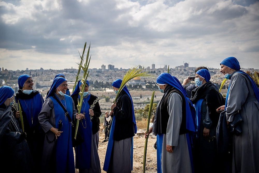 Christian pilgrims take part in the traditional Palm Sunday procession on the Mount of Olives, occupied East Jerusalem, March 28, 2021. (Yonatan Sindel/Flash90)