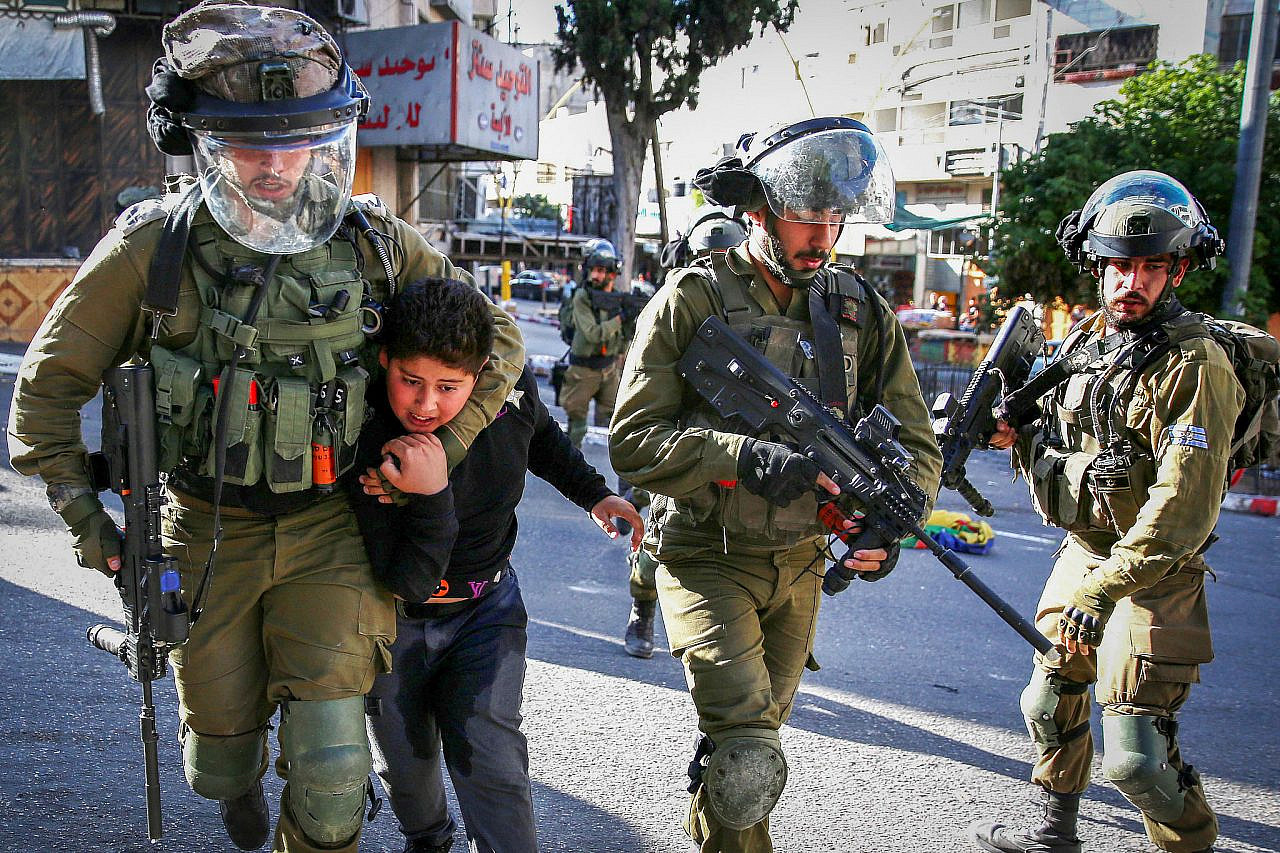 Israeli soldiers arrest a Palestinian boy as Israelis hold a tour of the West Bank city of Hebron during the Jewish holiday of Sukkot, September 23, 2021. (Wisam Hashlamoun/Flash90)