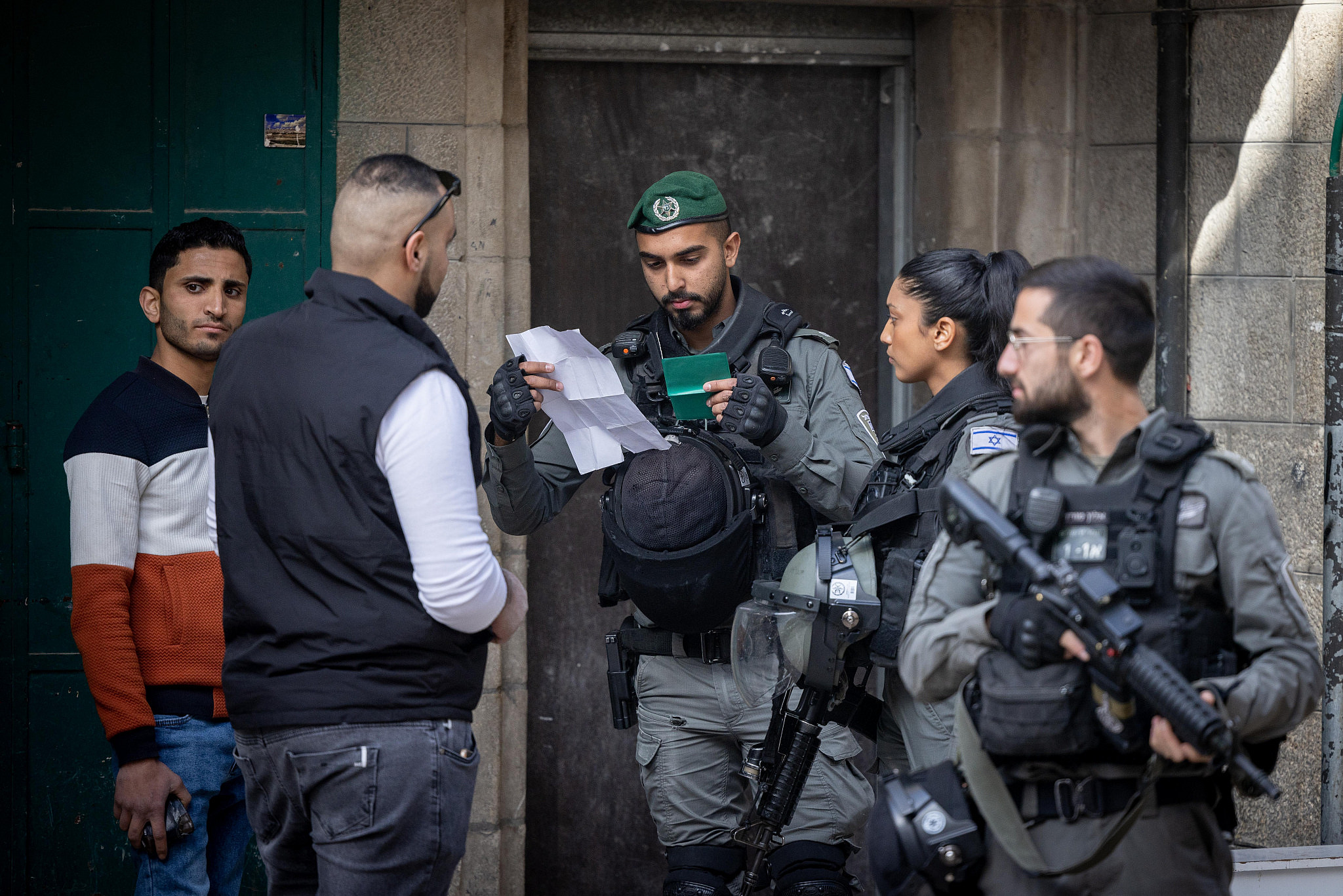 Israeli border police officers check a Palestinian man's ID in Jerusalem's Old City, April 1, 2022. (Yonatan Sindel/Flash90)