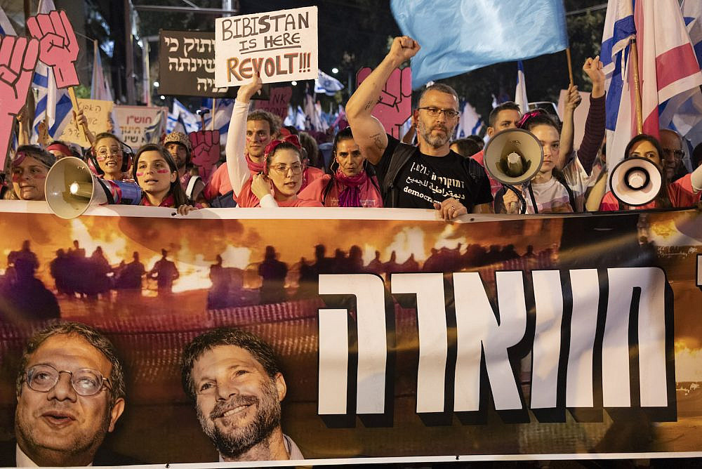 Israeli anti-government protesters hold up a sign in solidarity with Huwara following the pogrom on the town, Tel Aviv, March 5, 2023. (Oren Ziv)