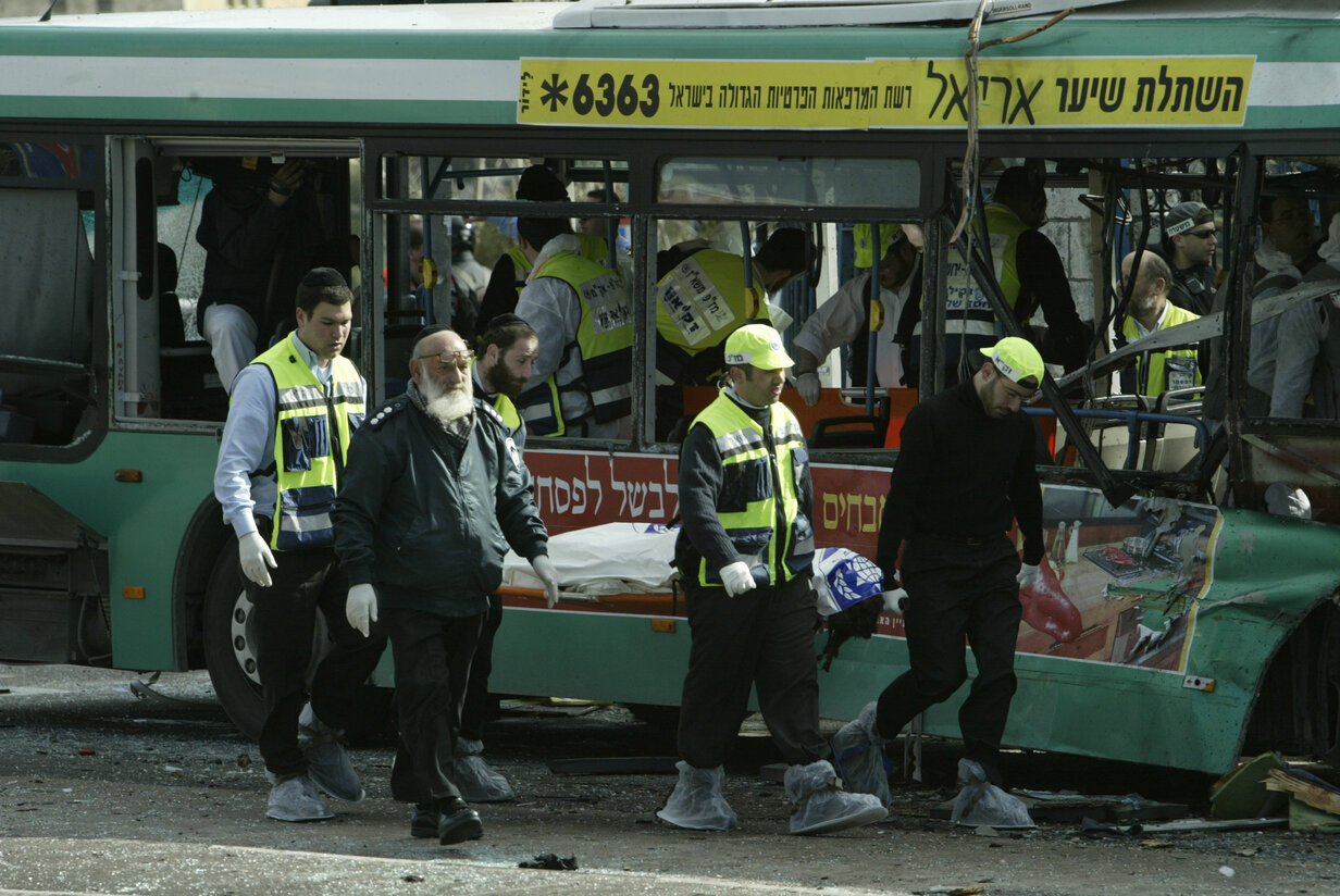 Paramedics and police carry away one of the victims killed in a suicide bombing on a bus that killed eight people and wounded over 60 in Jerusalem, February 22, 2004. (Flash90)