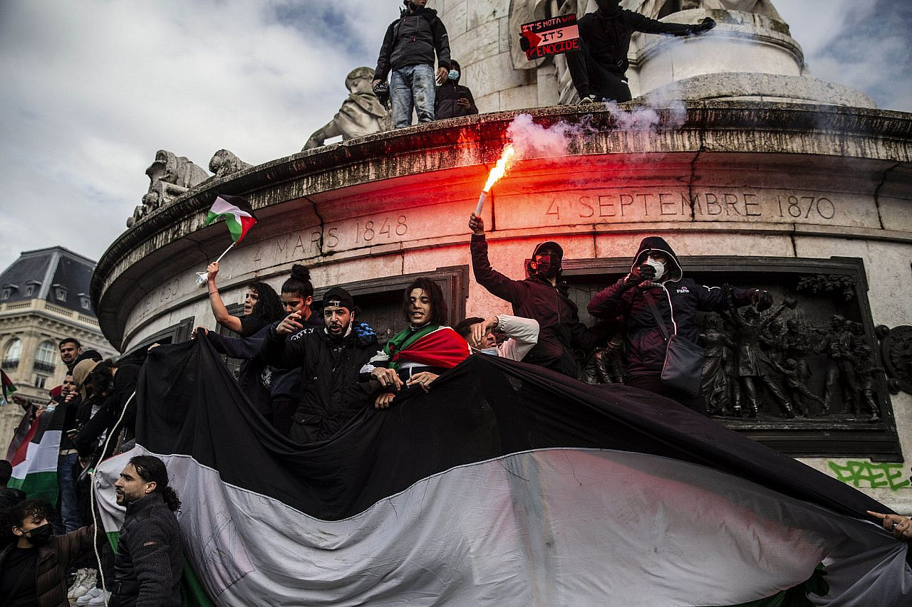 Protesters hold a huge Palestinian flag and use flares during a demonstration in Paris in support of Palestine, and to protest against the recent Israeli assault on the Gaza Strip and ongoing colonization and ethnic cleansing of the Palestinian people, France, May 15, 2001. (Anne Paq/Activestills)
